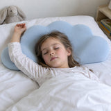 A girl of about six asleep on her back on the cloud pillow, one arm above her head